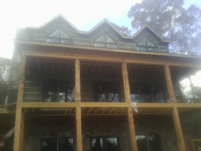 Dormers and porch framing on a large log home under construction — Roof Coating work by our crew in Lucerne