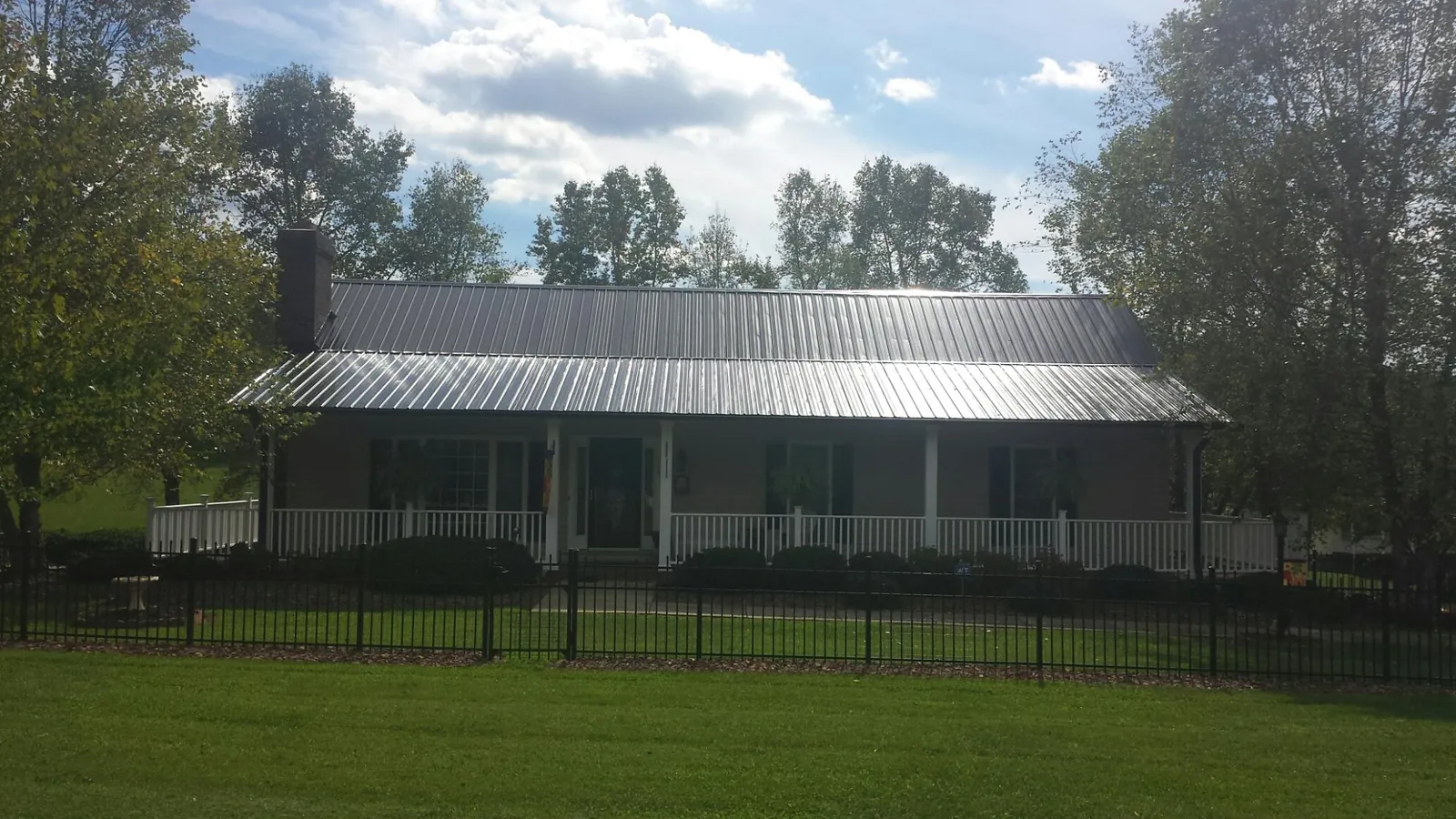 Gray metal roof on a brick ranch with a full width front porch — Gutter Guard Installation work by our crew in Lucerne