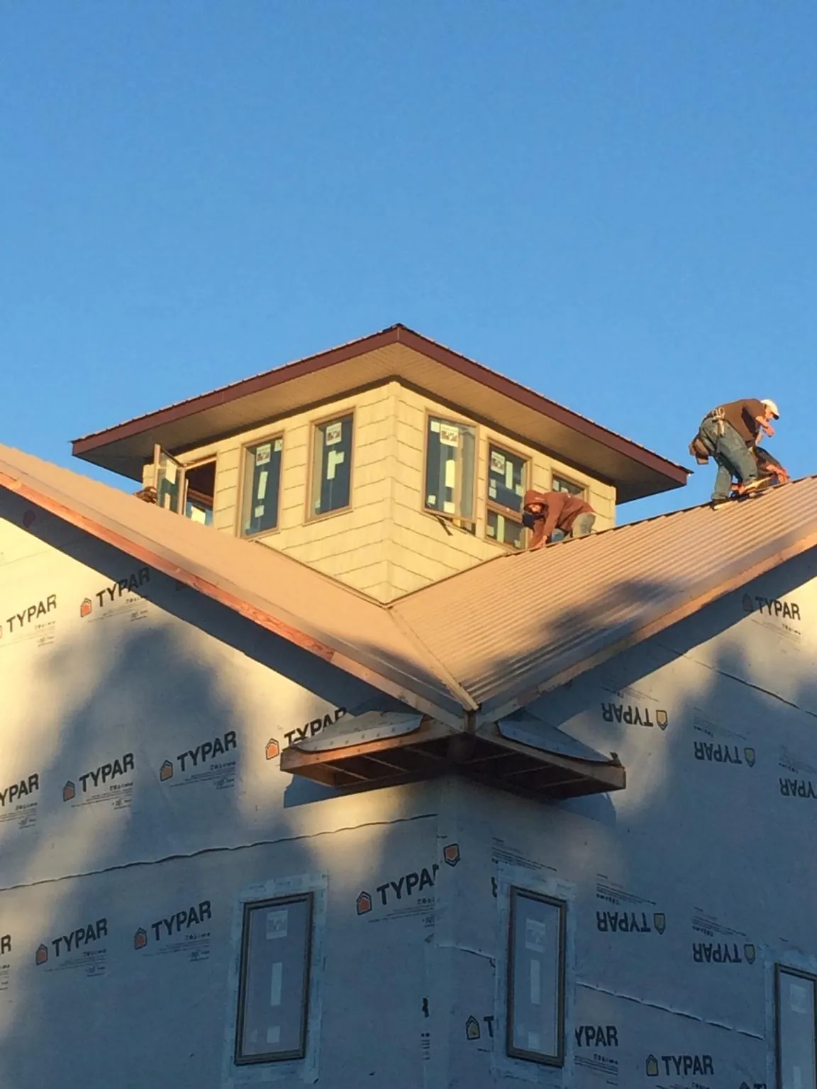 Roofers working around a rooftop cupola on a new metal roof at sunset — Roof Waterproofing in Lucerne by Roofing Brothers